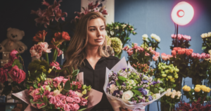 Florist arranging a colorful bouquet of fresh flowers in a floral shop, surrounded by seasonal blooms and greenery.